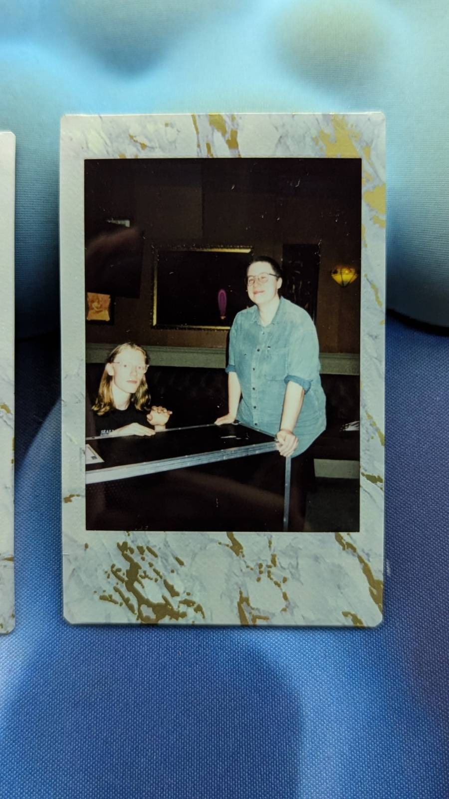 Poloroid photo of Charlotte and Jo in The County, Charlotte is leaning against a flight case, Jo is crouched behind it like a lil sound gremlin.