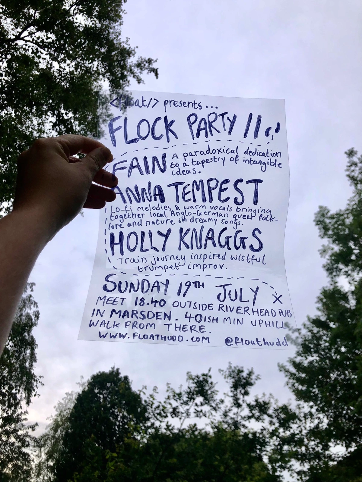 Gig poster containing the event details listed below written on a piece of acetate and held up against a blue sky.
