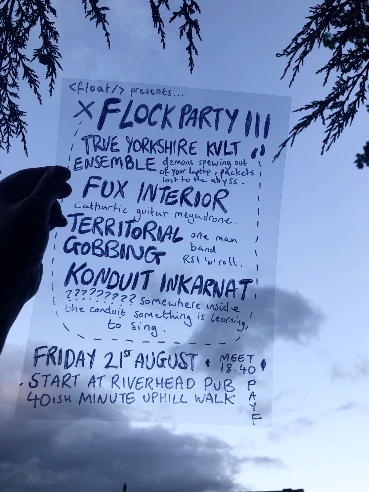 Gig poster containing the event details listed below written on a piece of acetate and held up against a blue sky.