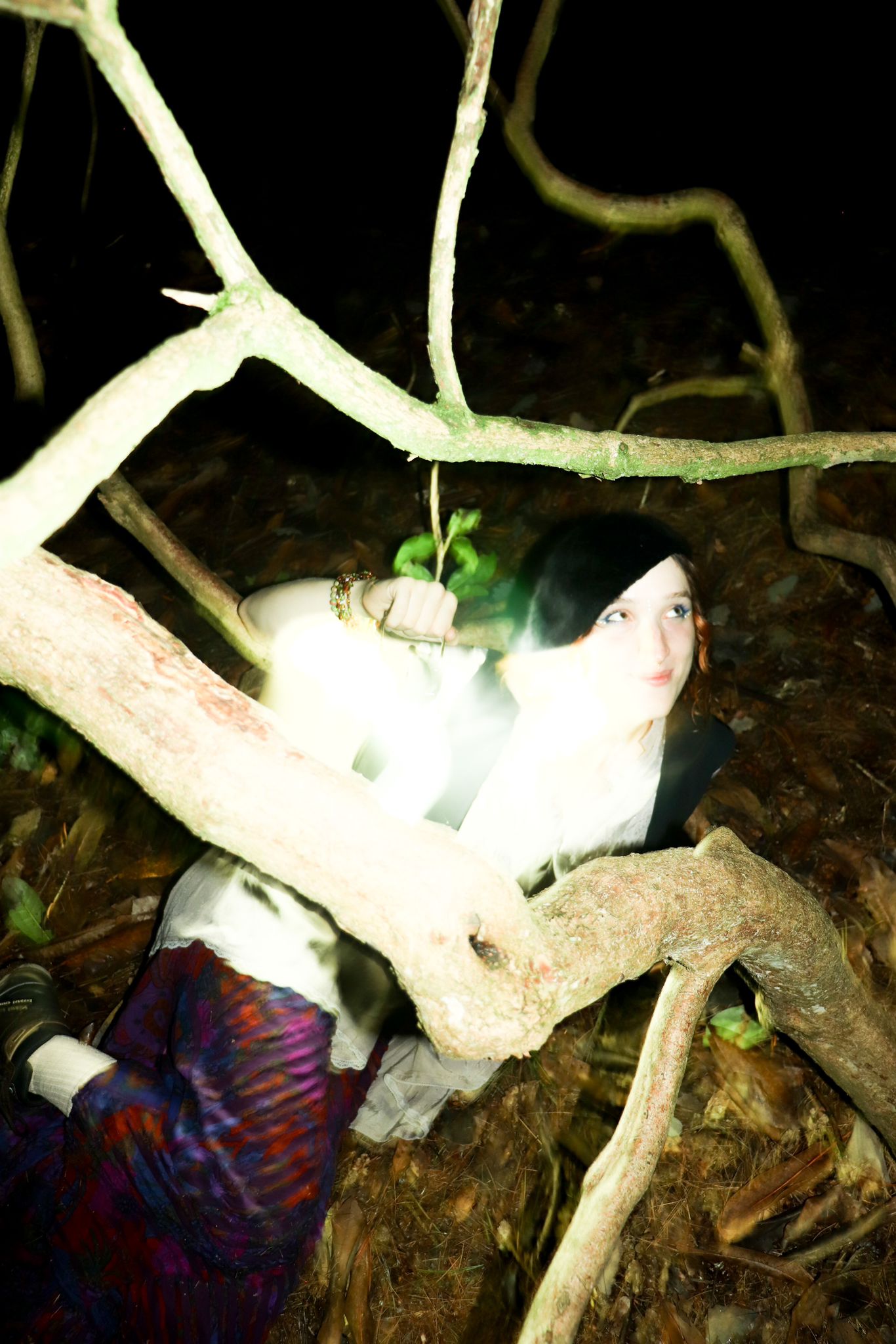 Photo of Layla in the woods. It's dark and a bright flash from the camera illuminates the image.